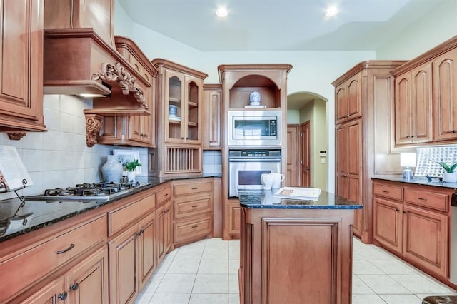 kitchen featuring light tile patterned flooring, a center island, appliances with stainless steel finishes, and dark stone countertops