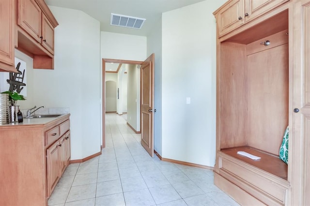 interior space featuring visible vents, baseboards, arched walkways, a sink, and light tile patterned floors
