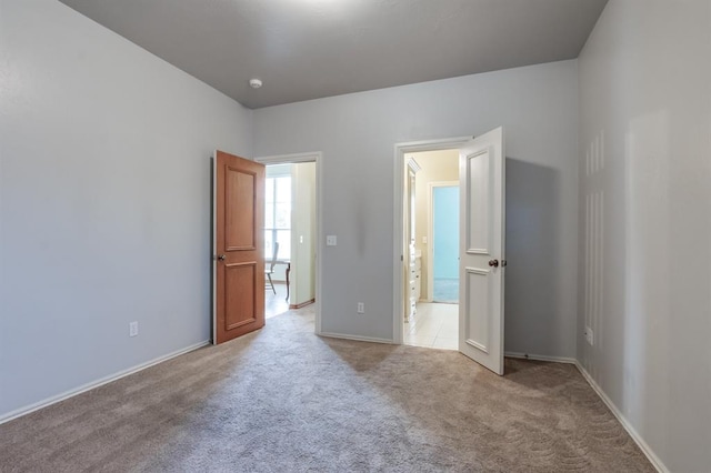unfurnished bedroom with light colored carpet and baseboards