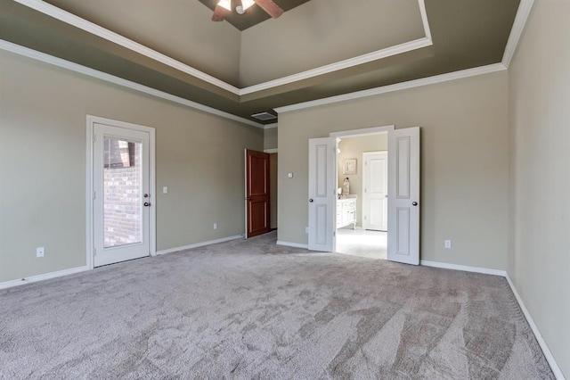 spare room featuring a raised ceiling, ornamental molding, carpet, and a ceiling fan