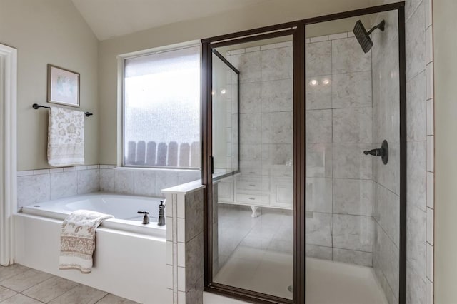 full bathroom featuring tile patterned flooring, vaulted ceiling, a garden tub, and a shower stall
