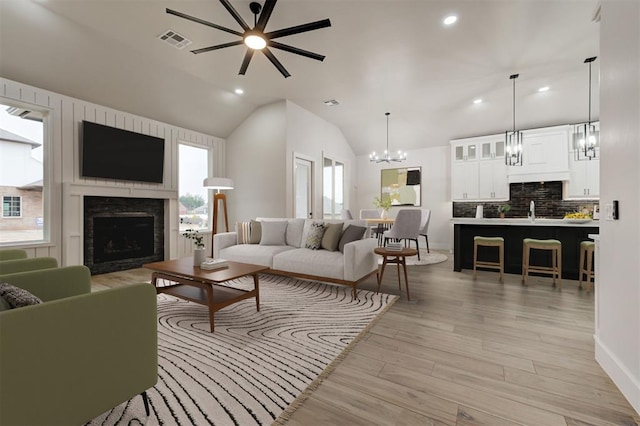 living room featuring ceiling fan, light wood-type flooring, a healthy amount of sunlight, and vaulted ceiling