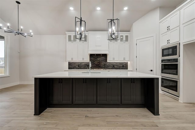 kitchen with white cabinetry, built in microwave, a large island, and decorative light fixtures