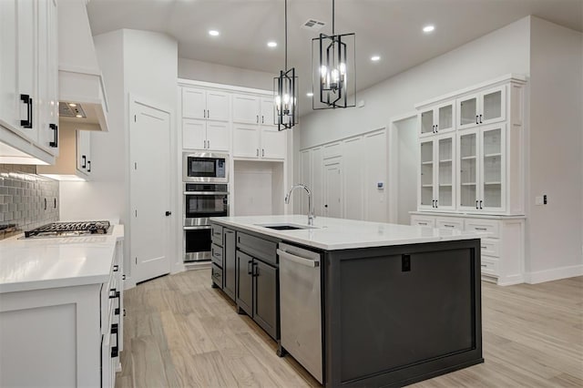 kitchen featuring white cabinetry, an island with sink, tasteful backsplash, pendant lighting, and sink