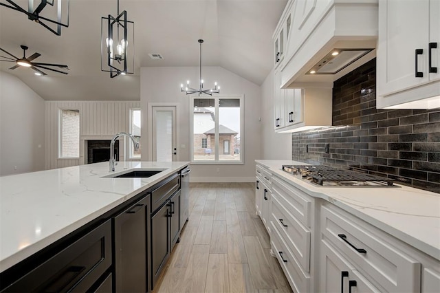 kitchen with vaulted ceiling, pendant lighting, white cabinets, and sink