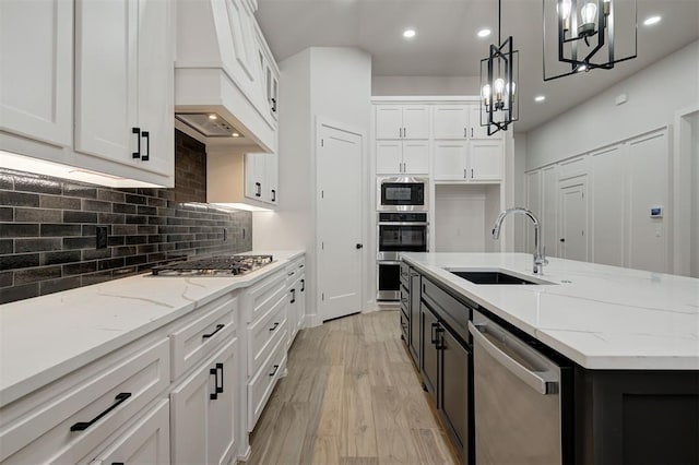 kitchen with hanging light fixtures, sink, white cabinetry, and stainless steel appliances