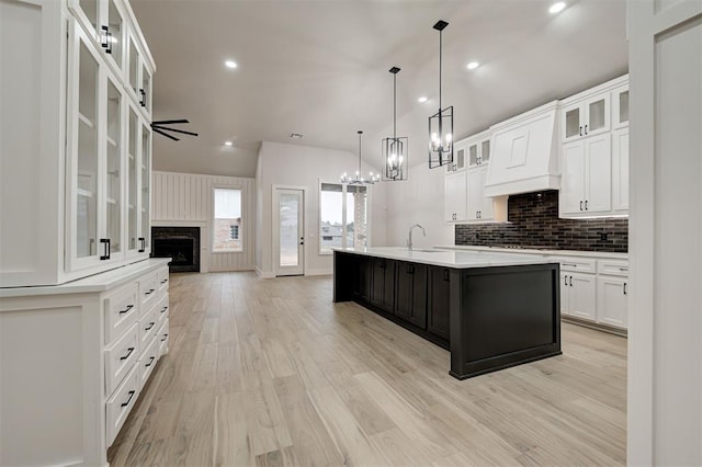 kitchen with light hardwood / wood-style floors, pendant lighting, sink, white cabinetry, and a kitchen island with sink