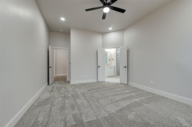 unfurnished bedroom with ceiling fan, light colored carpet, a high ceiling, and connected bathroom