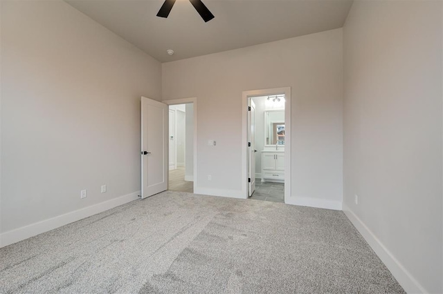 unfurnished bedroom with ceiling fan, ensuite bathroom, and light carpet