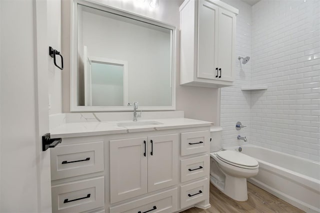 full bathroom featuring hardwood / wood-style flooring, tiled shower / bath combo, vanity, and toilet