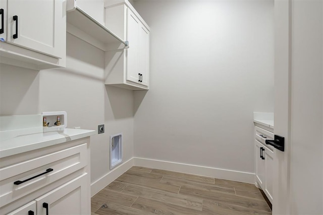 clothes washing area featuring light wood-type flooring, electric dryer hookup, hookup for a washing machine, and cabinets