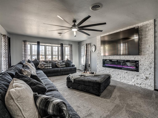 living room featuring ceiling fan, carpet, and a stone fireplace