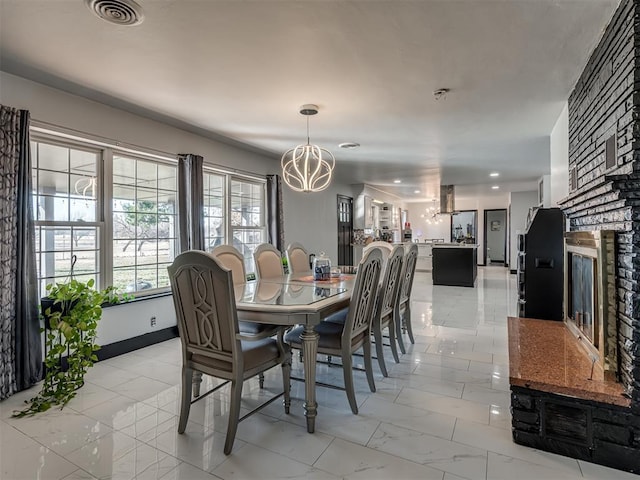 dining area featuring a fireplace and a chandelier