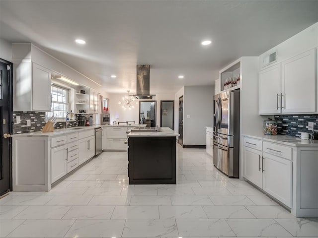 kitchen featuring white cabinets, stainless steel appliances, a kitchen island, and tasteful backsplash