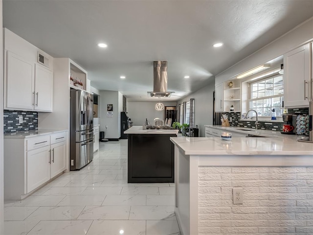 kitchen with kitchen peninsula, decorative backsplash, stainless steel refrigerator with ice dispenser, sink, and white cabinets