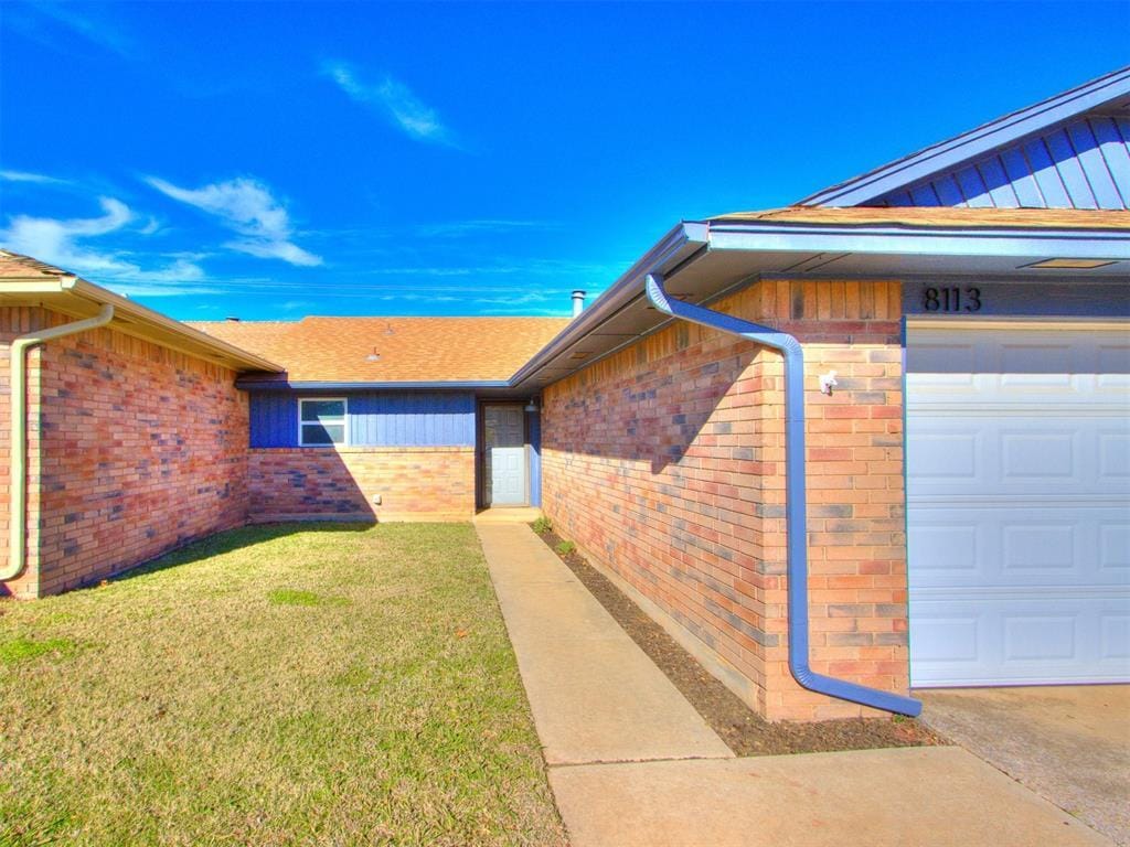 view of exterior entry featuring a yard and a garage