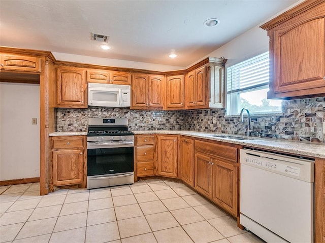 kitchen with decorative backsplash, sink, light tile patterned floors, and white appliances