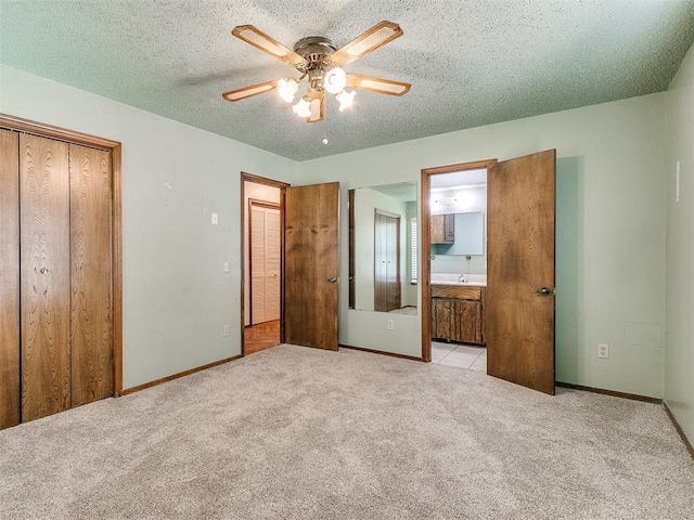 unfurnished bedroom with ensuite bathroom, ceiling fan, light colored carpet, and a textured ceiling