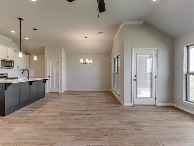 kitchen featuring white cabinets, light hardwood / wood-style floors, hanging light fixtures, and appliances with stainless steel finishes