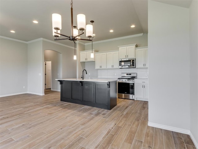 kitchen with pendant lighting, light wood-type flooring, white cabinetry, and appliances with stainless steel finishes