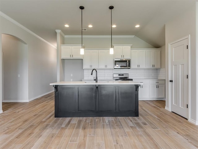 kitchen with white cabinetry, stainless steel appliances, decorative light fixtures, and light hardwood / wood-style floors