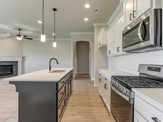 kitchen featuring pendant lighting, a center island with sink, white cabinets, sink, and appliances with stainless steel finishes