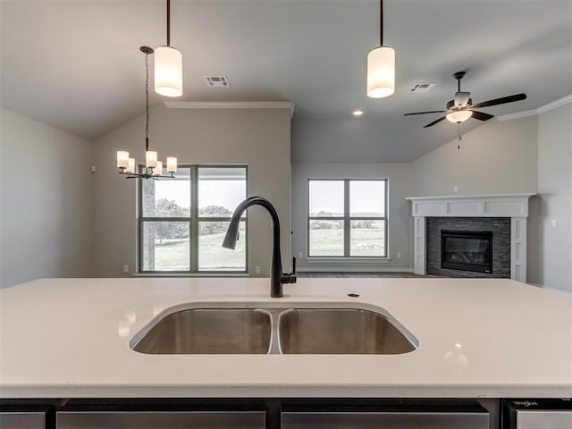 kitchen featuring lofted ceiling, sink, hanging light fixtures, ornamental molding, and a fireplace