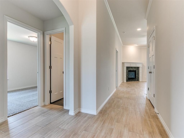 corridor with light hardwood / wood-style floors and ornamental molding