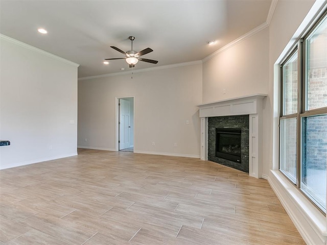 unfurnished living room featuring a high end fireplace, light hardwood / wood-style floors, ceiling fan, and ornamental molding