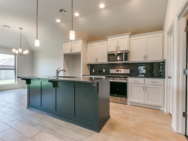 kitchen featuring a center island with sink, sink, decorative light fixtures, white cabinetry, and stainless steel appliances