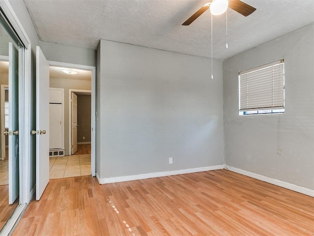 spare room featuring ceiling fan, light hardwood / wood-style floors, and a textured ceiling