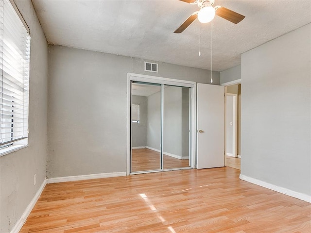 unfurnished bedroom with ceiling fan, a closet, and light wood-type flooring