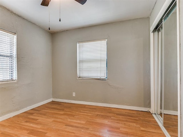 unfurnished bedroom with multiple windows, ceiling fan, a closet, and light hardwood / wood-style floors