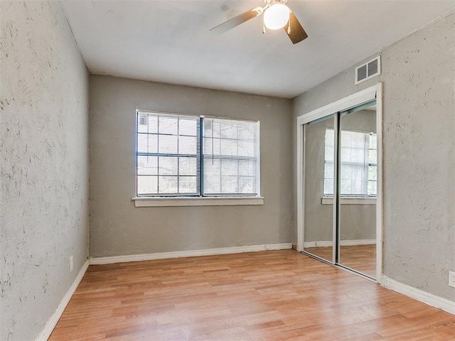 unfurnished bedroom featuring a closet, light hardwood / wood-style floors, and ceiling fan