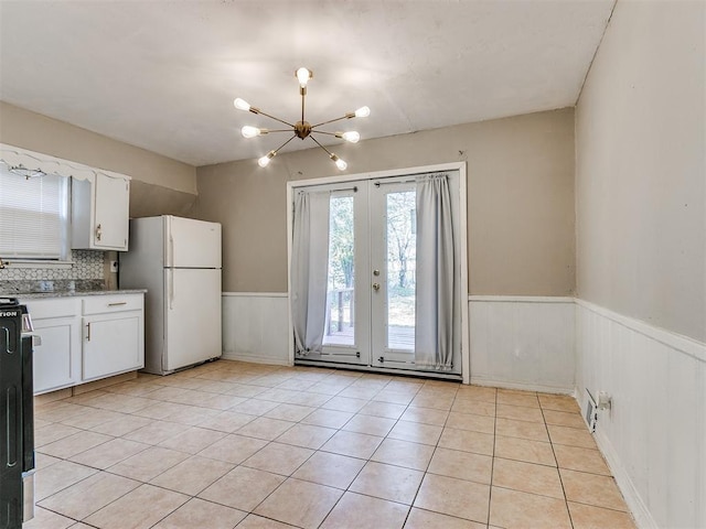 kitchen featuring white cabinets, decorative backsplash, light tile patterned floors, and white refrigerator