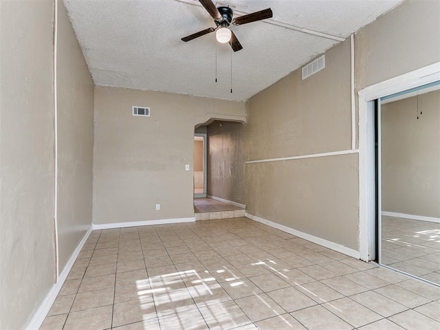 empty room featuring light tile patterned floors, a textured ceiling, and ceiling fan