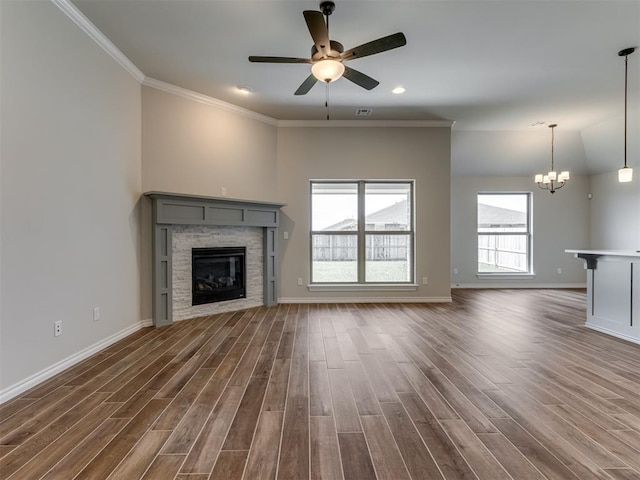 unfurnished living room featuring crown molding, a fireplace, ceiling fan with notable chandelier, and dark hardwood / wood-style floors