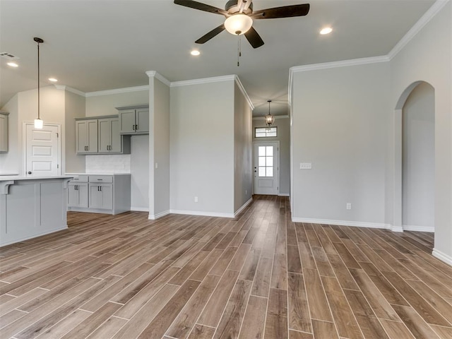 unfurnished living room featuring hardwood / wood-style floors, ceiling fan, and crown molding