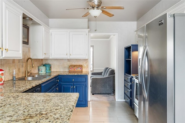 kitchen with white cabinets, stainless steel fridge, blue cabinets, and sink