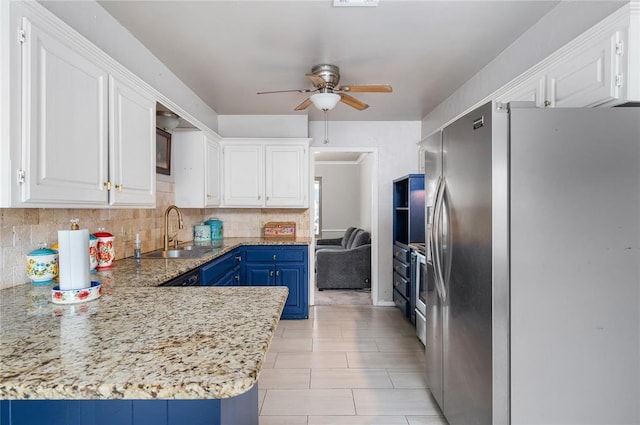 kitchen featuring stainless steel fridge, tasteful backsplash, blue cabinets, sink, and white cabinets