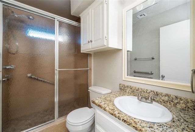 bathroom featuring vanity, toilet, and a shower with door