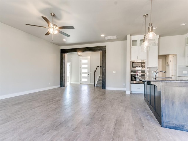 kitchen with appliances with stainless steel finishes, ceiling fan, decorative light fixtures, light hardwood / wood-style flooring, and white cabinets