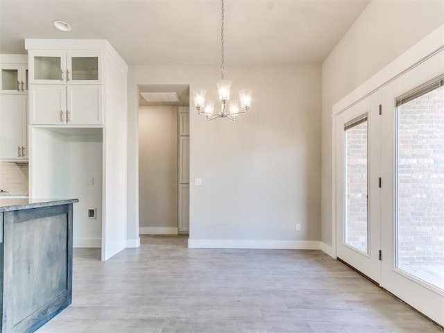 kitchen featuring decorative backsplash, white cabinetry, light hardwood / wood-style floors, and decorative light fixtures