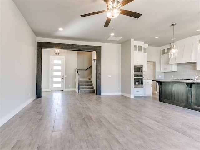 kitchen featuring decorative backsplash, appliances with stainless steel finishes, light wood-type flooring, white cabinetry, and hanging light fixtures