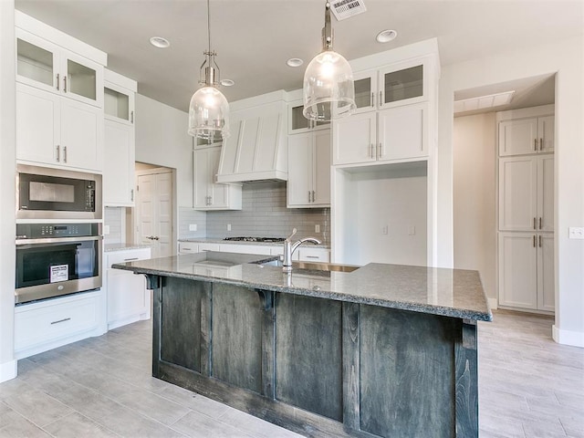 kitchen featuring stone countertops, a kitchen island with sink, and appliances with stainless steel finishes