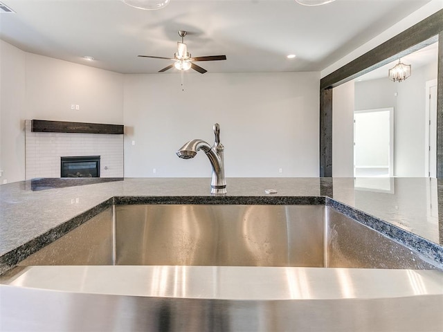 interior space featuring ceiling fan with notable chandelier, a brick fireplace, and sink