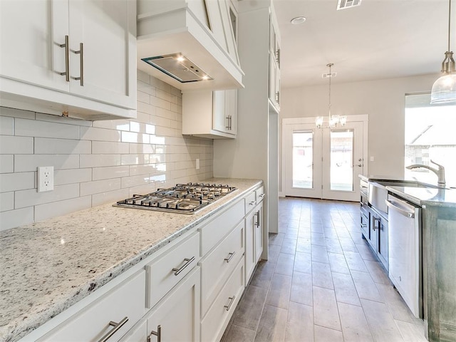 kitchen featuring custom range hood, white cabinetry, hanging light fixtures, and stainless steel appliances