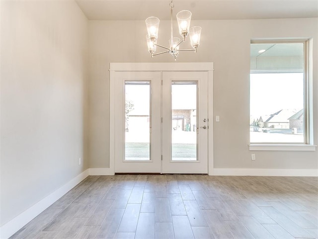 doorway to outside with light hardwood / wood-style flooring and a notable chandelier