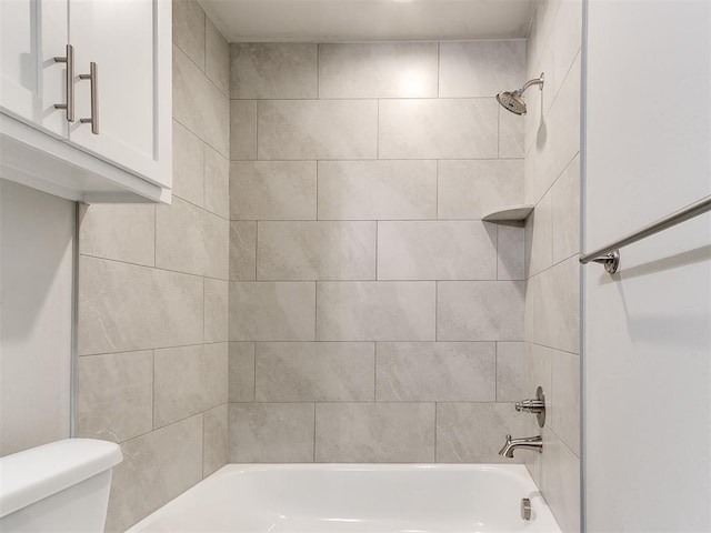 bathroom with tiled shower / bath combo and toilet