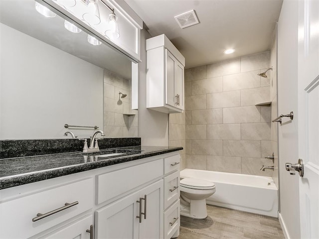 full bathroom with vanity, toilet, wood-type flooring, and tiled shower / bath